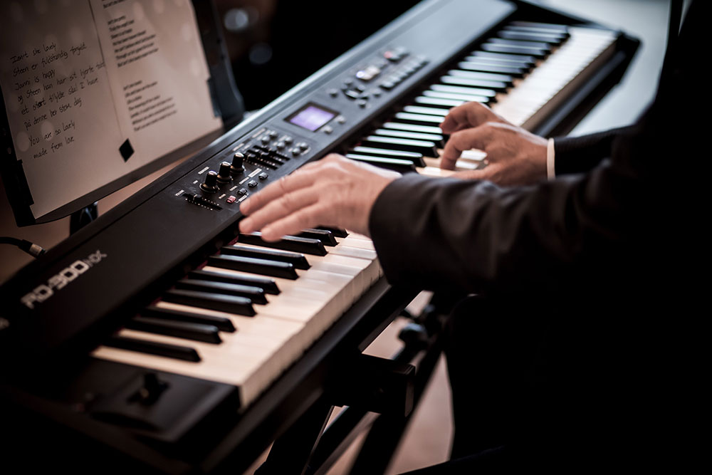 Ein Keyboardspieler im Anzug spielt einen Dreiklang