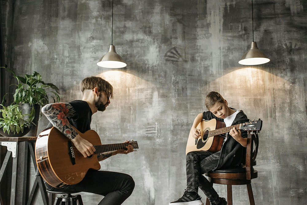 Ein Gitarrelehrer beobachtet seinen Schüler, während dieser Akkorde lernt