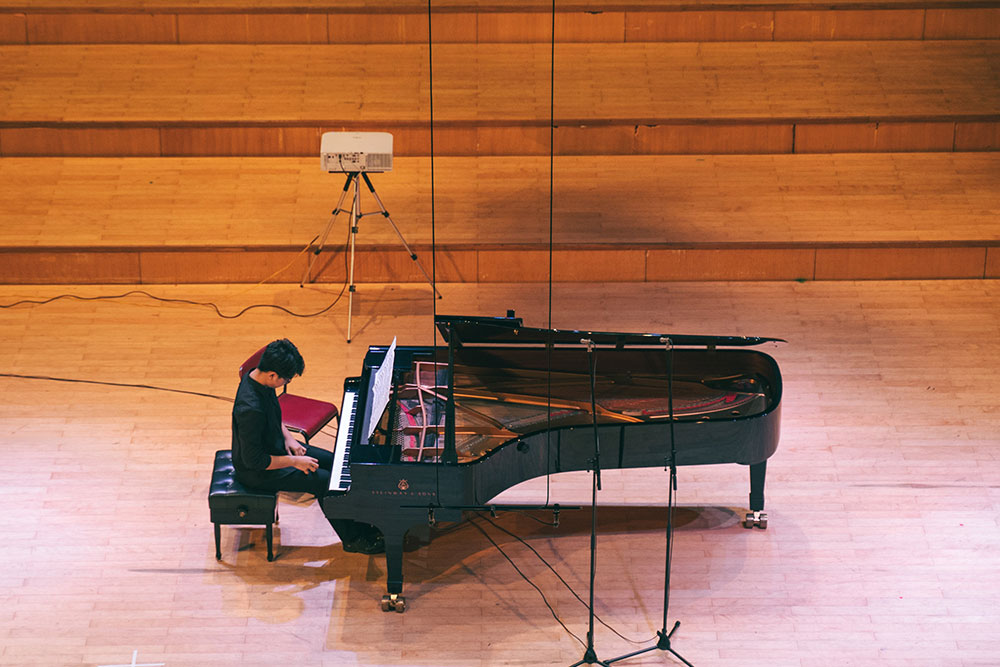 Ein Pianist sitzt vor einem Konzertflügel und macht sich zum musizieren bereit