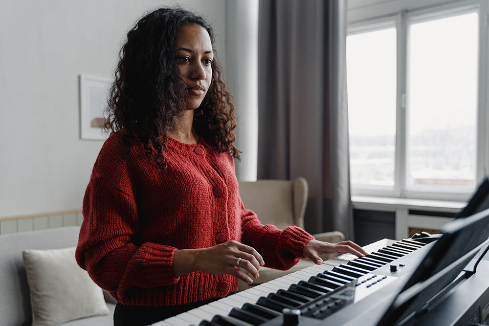 Eine lockige Klavierspielerin übt das Instrument in ihrer Wohnung